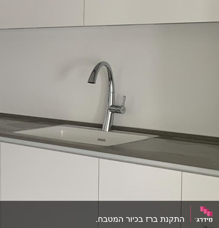 ברז מטבח כסוף מותקן על כיור לבן